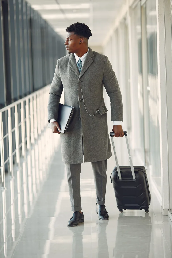 Voyageur en manteau avec sa valise dans un aéroport